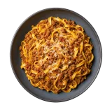 Tagliatelle al ragu alla bolognese in a dark stoneware bowl, topped with grated parmesan