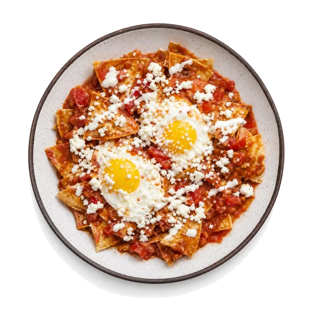 Chilaquiles plated with corn tortilla, tomato, chili