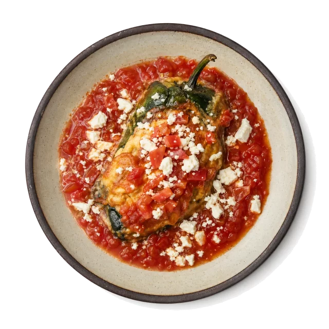 Chiles Rellenos plated with bell pepper, queso fresco, tomato