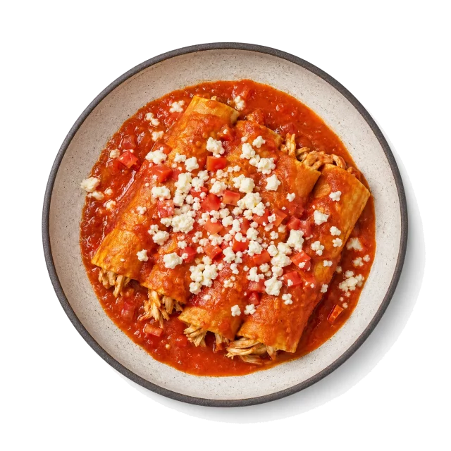 Enchiladas plated with corn tortilla, chicken, tomato