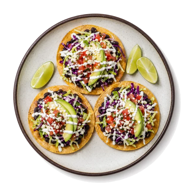 Tostadas plated with corn tortilla, black beans, tomato