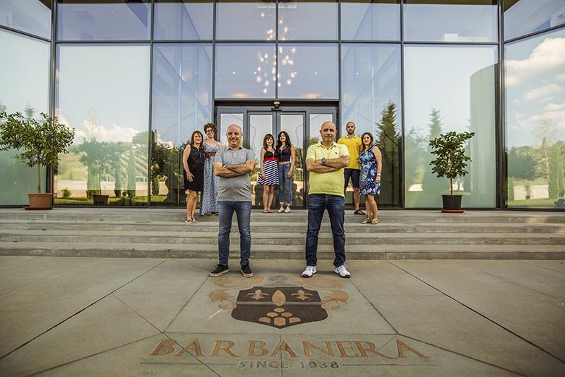 The Barbanera family and team standing in front of the winery's glass entrance