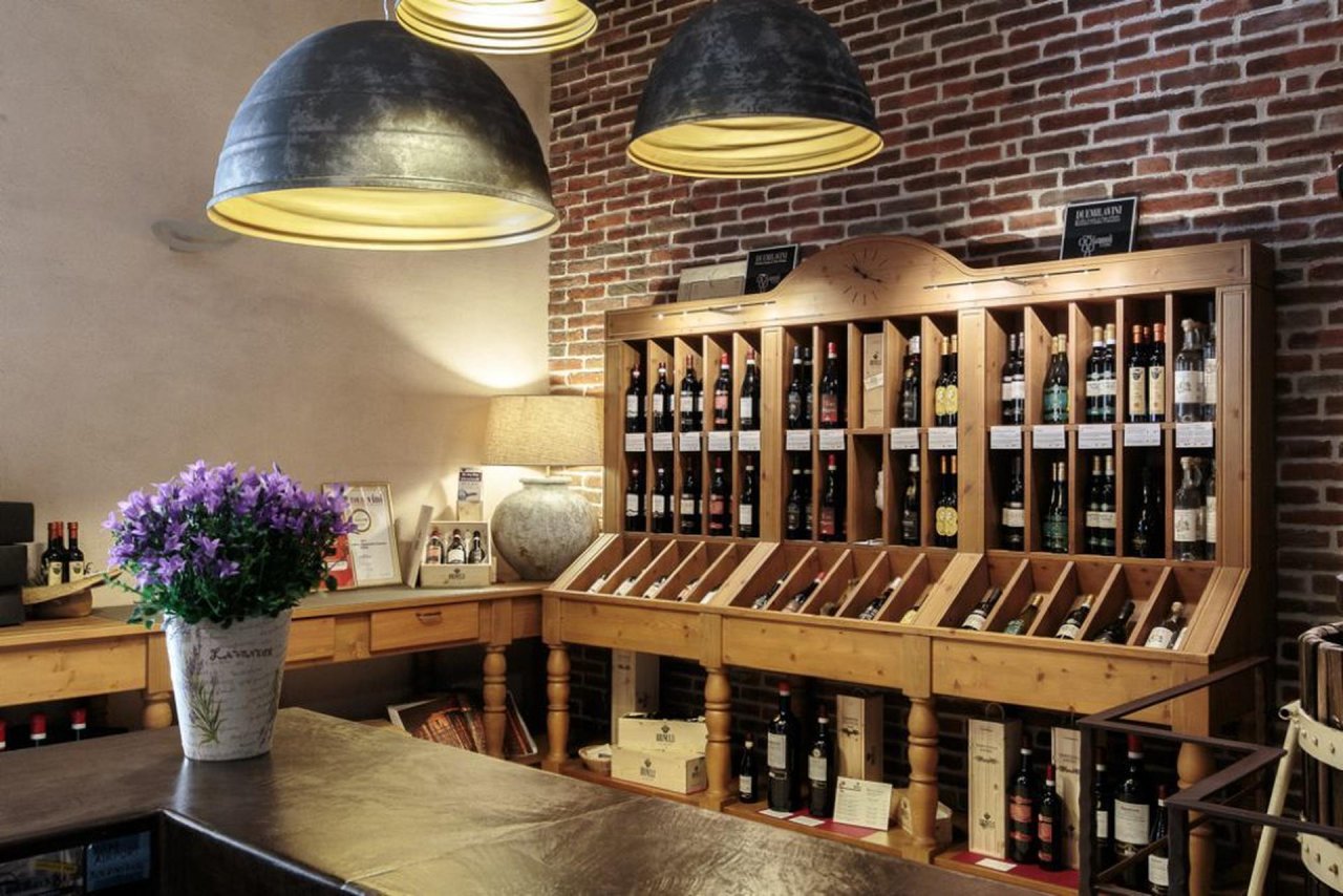 The Brunelli wine shop, with bottles on wooden shelves under pendant lamps and flowers on the counter