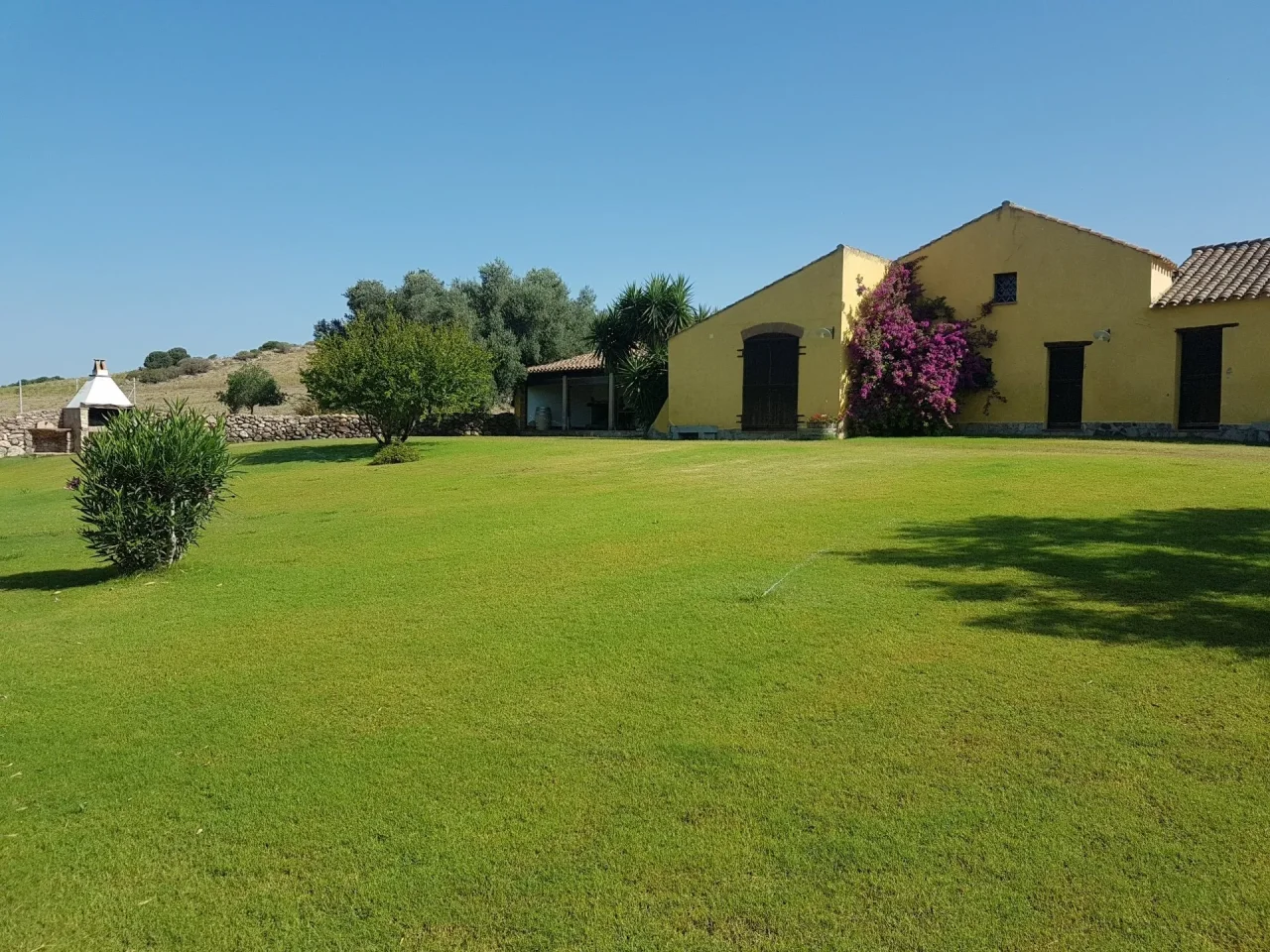 The yellow farmhouse of Agricola Punica at Santadi behind a wide green lawn