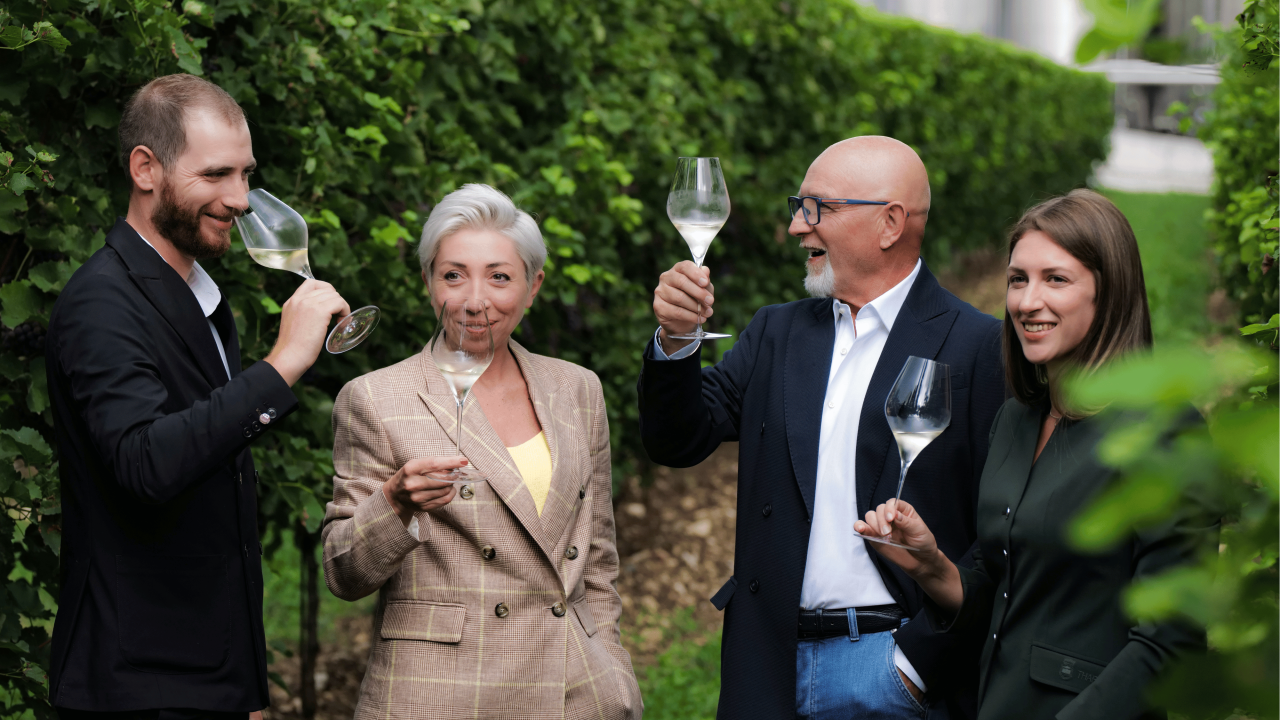 Four members of the Pizzolato family raising glasses among the vines