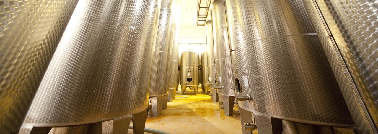 Rows of tall stainless steel tanks in the Araldica cellar at Castel Boglione