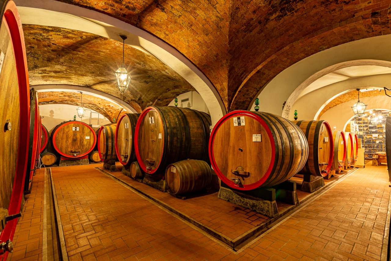Vaulted brick cellar at Fattoria Svetoni, lined with large oak casks with red hoops