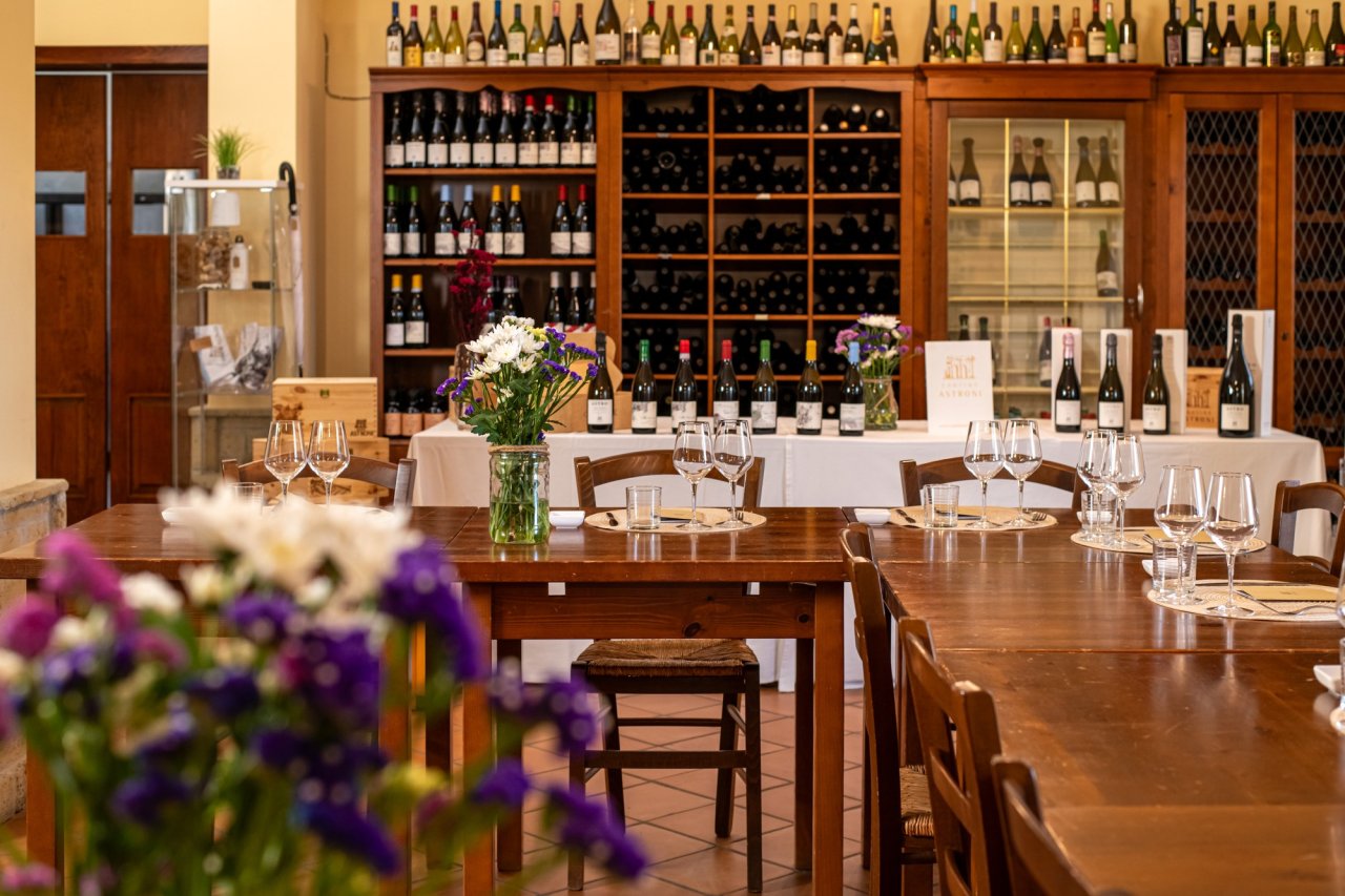 The Cantine degli Astroni tasting room, with wooden tables laid with glasses and shelves of wine