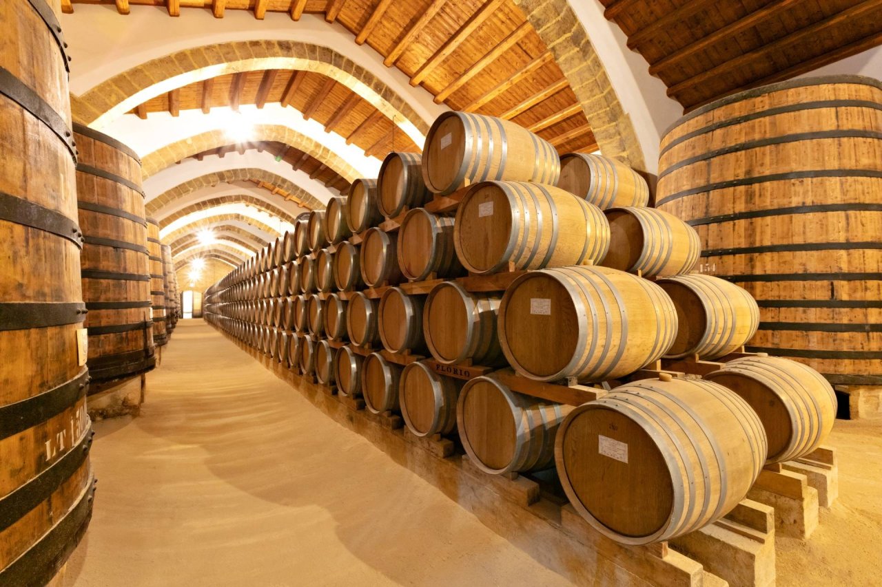 Rows of oak casks in a long aisle of the Florio cellars in Marsala