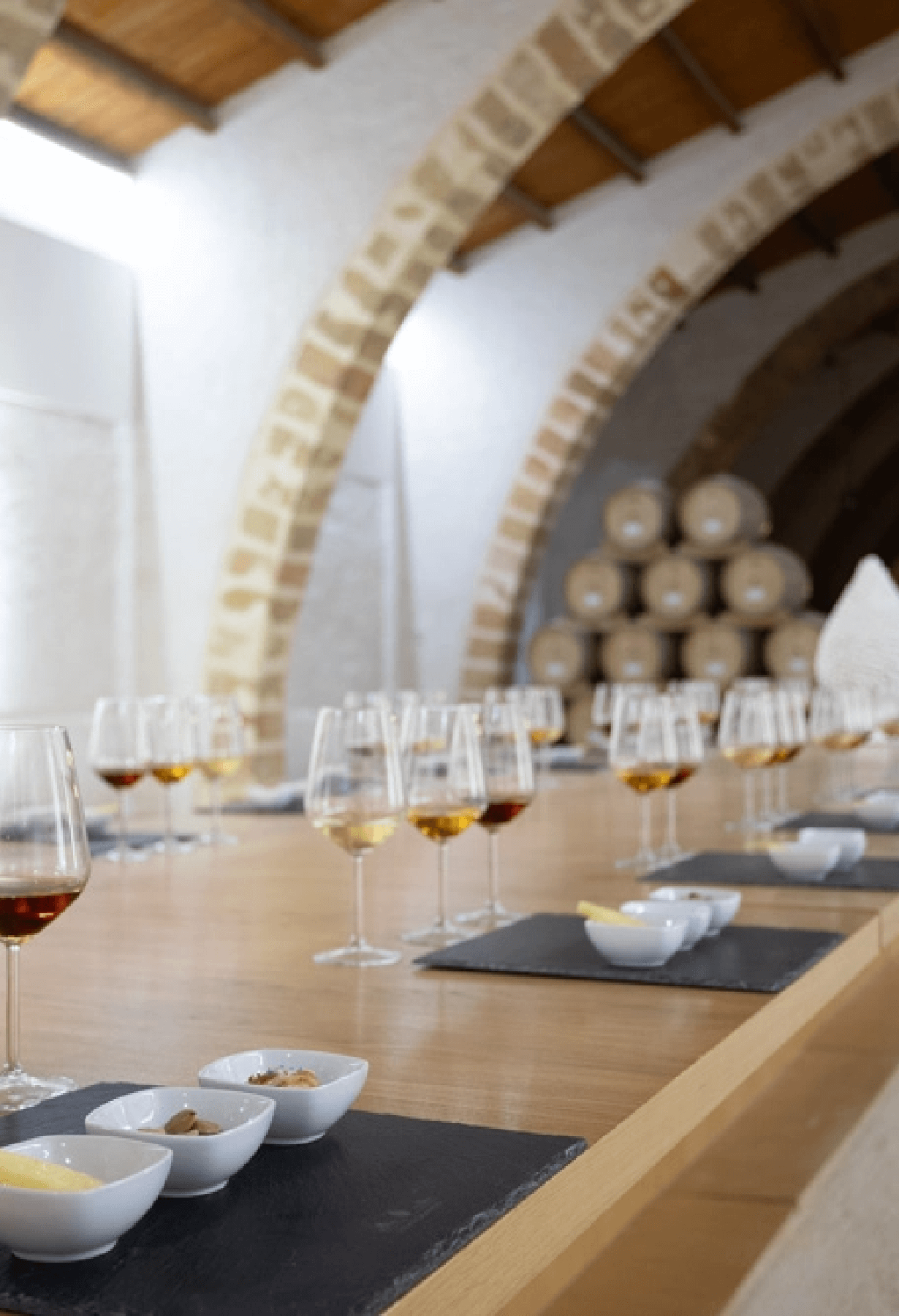 Tasting room under the pointed tufa arches of Cantine Florio, glasses set out on a long table