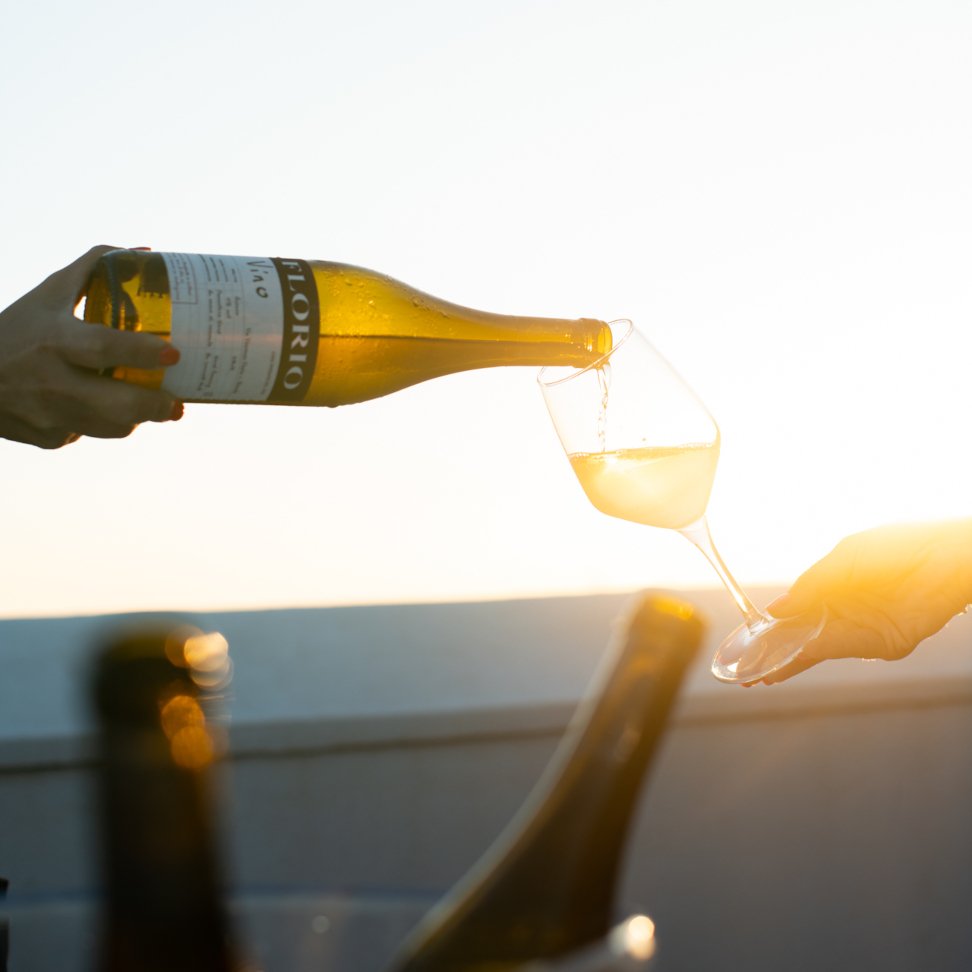 A bottle of Florio Marsala poured into a glass against the sunlit sea at Marsala