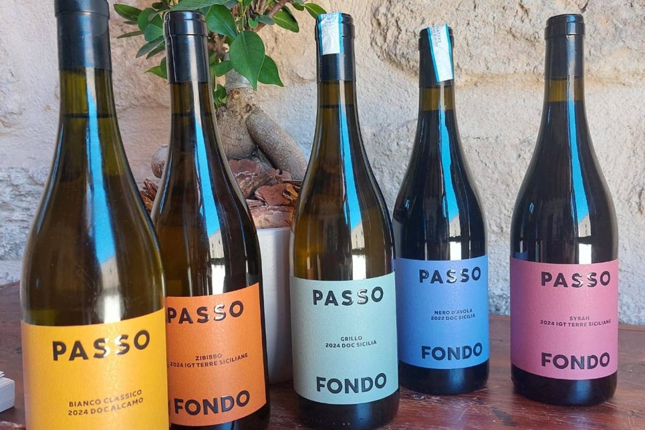 Five Passofondo bottles from Tenute Baglio Passofondo lined up against a stone wall, including its Alcamo DOC white