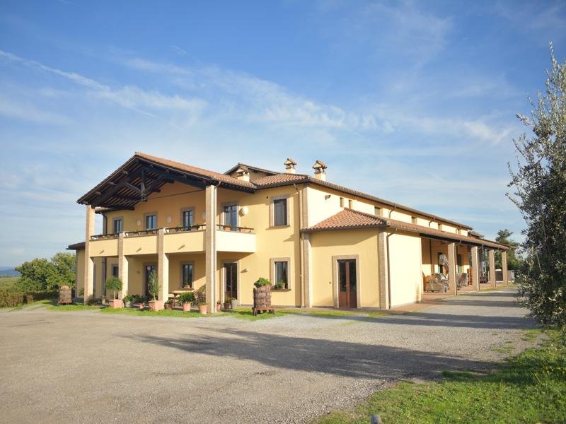 The Cantina Custodi winery, a long pale yellow building with a covered portico and an upstairs loggia