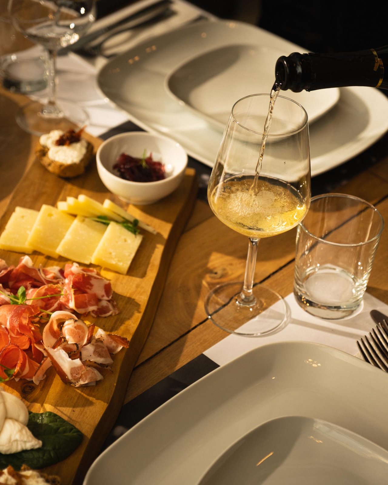 Sparkling wine being poured beside a board of cheese and cured meats at a Polvanera tasting