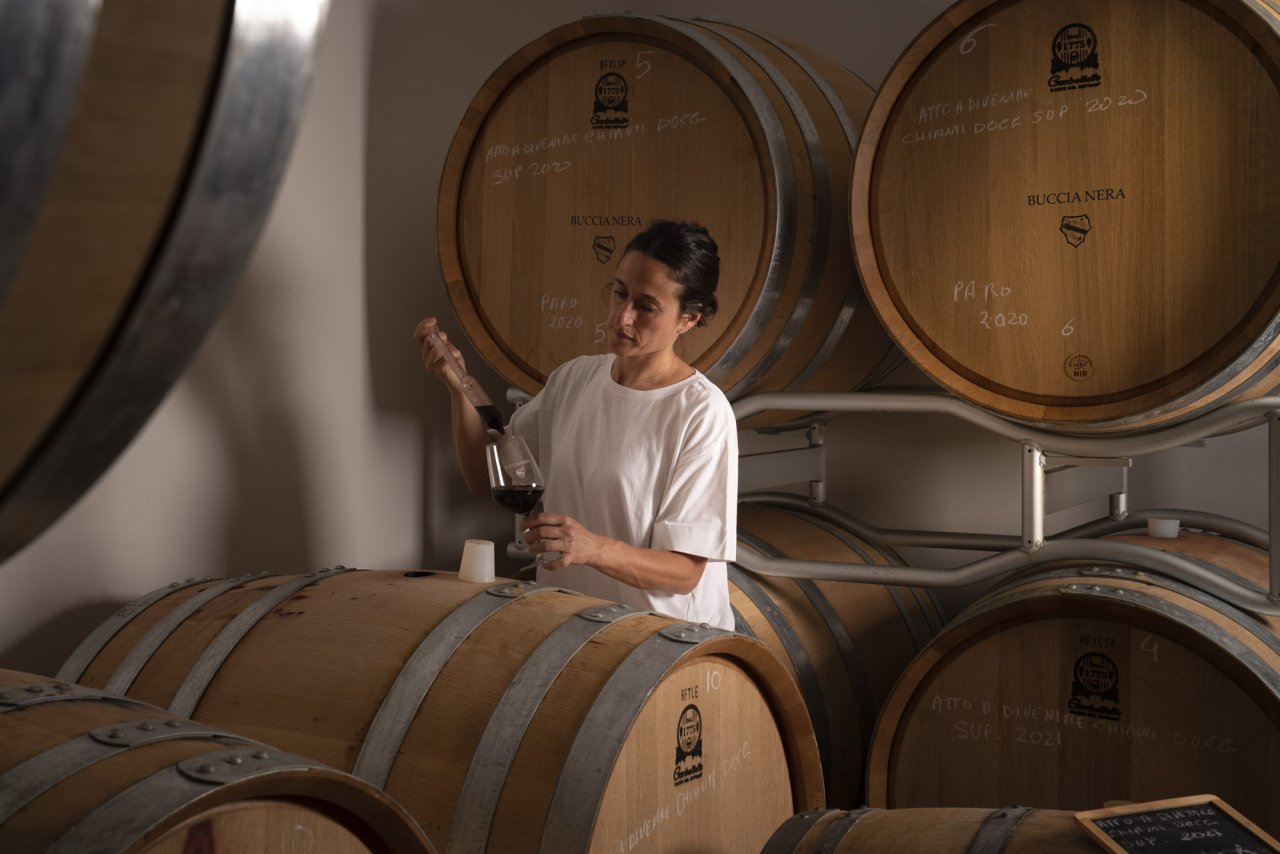 A woman draws a sample of red wine from an oak barrel in the Buccia Nera cellar