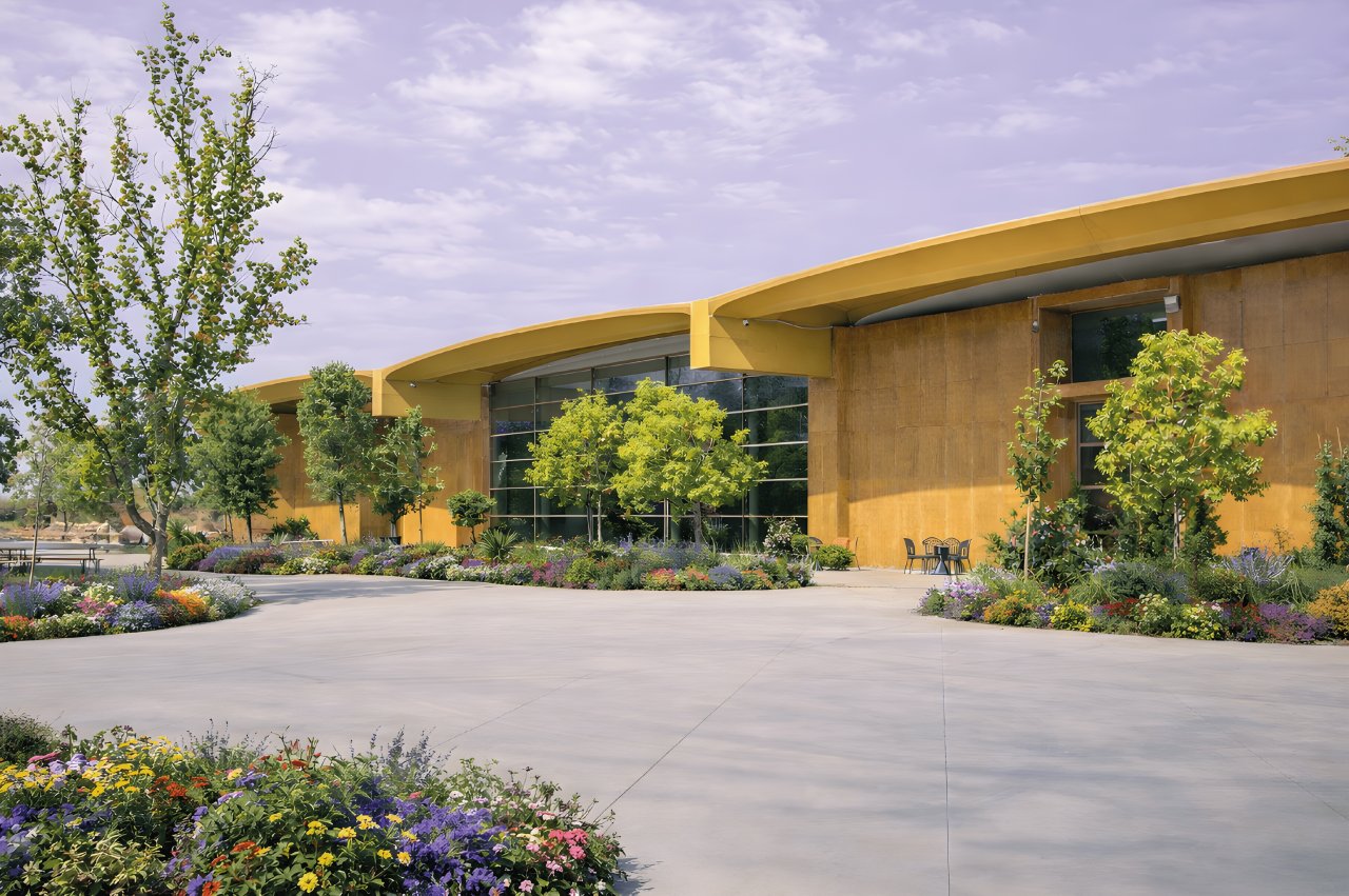 The Nativ winery building at San Quirico, with curved yellow roofs, a glass front and flower beds