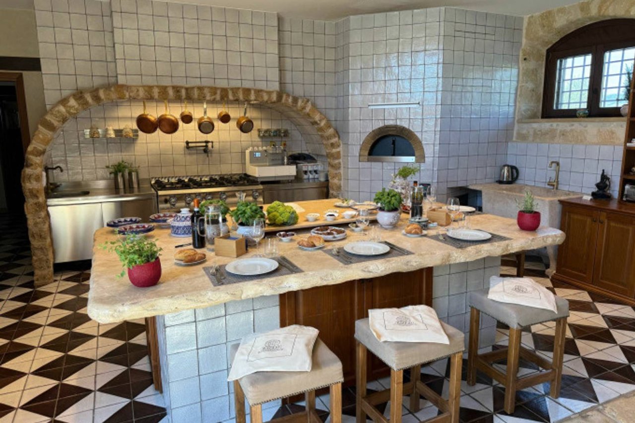 The tiled cooking-class kitchen at Tenute Baglio Passofondo, with copper pans over the stove and a long stone table