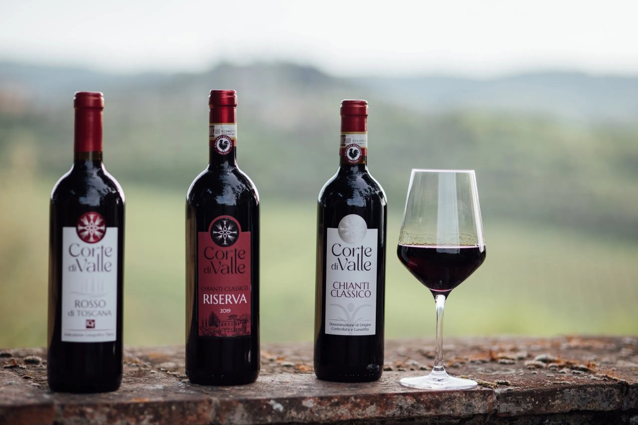 Bottles of Corte di Valle Rosso di Toscana, Chianti Classico Riserva 2019 and Chianti Classico beside a glass of red wine