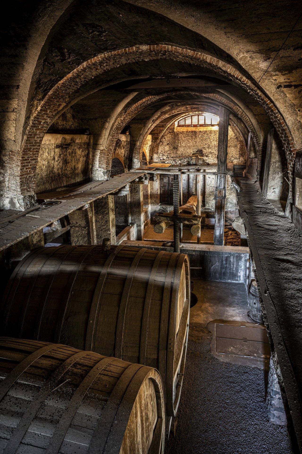 Inside Graci's old stone winery, a wooden cask beside the vaulted press room