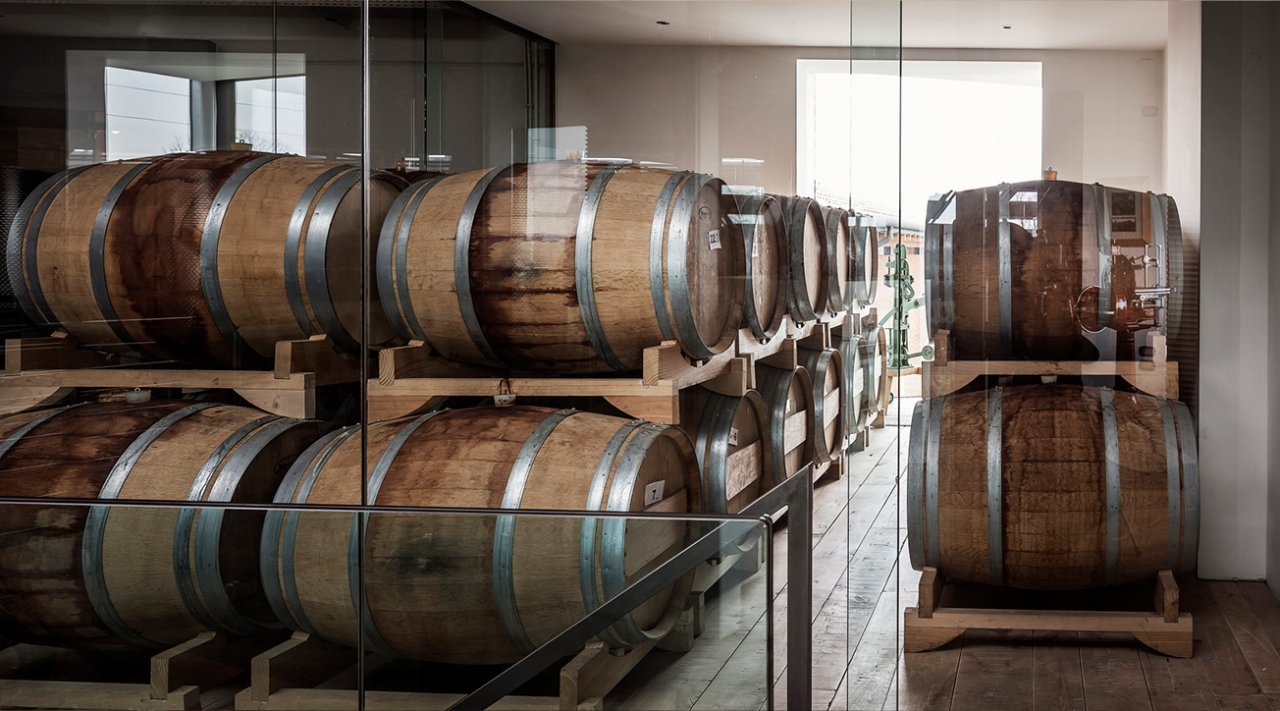 Rows of oak barrels on metal racks in the 47 Anno Domini barrel room