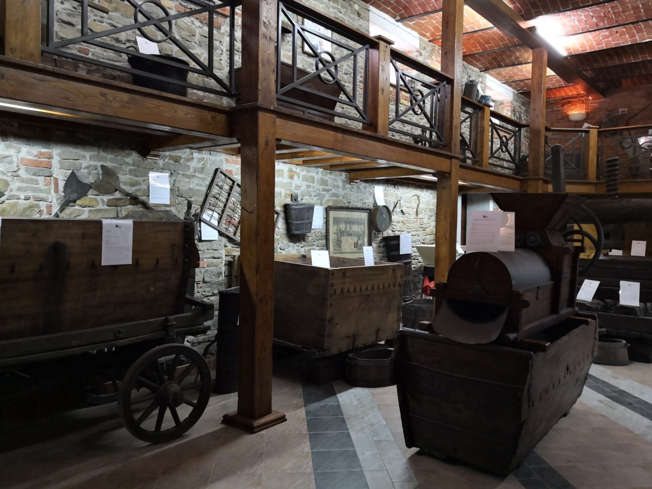 Inside the Museo Enologico Toso: an old cart, wooden vats and a balcony hung with farm tools