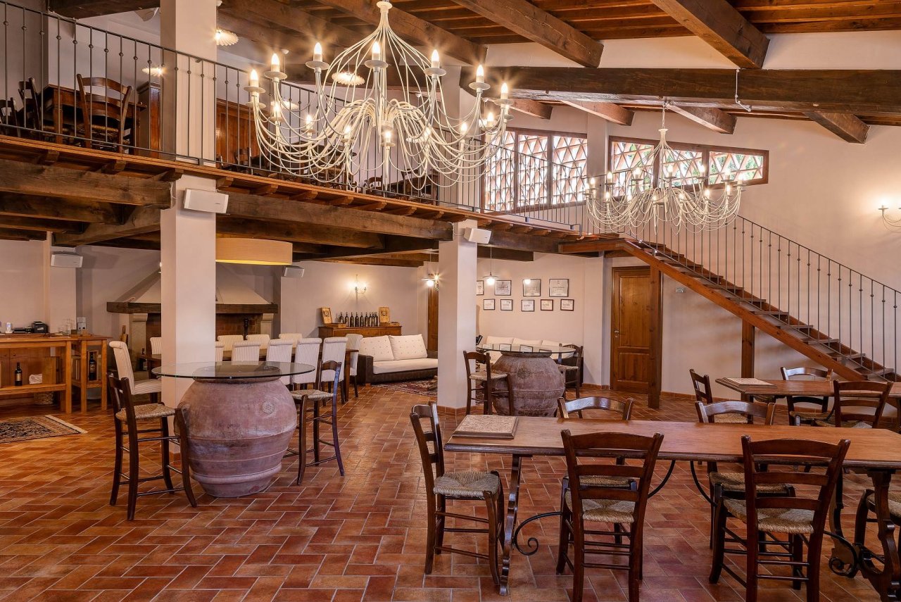 The tasting room at Lamole di Lamole, with wooden tables, a round table on a terracotta jar and chandeliers under the beamed ceiling