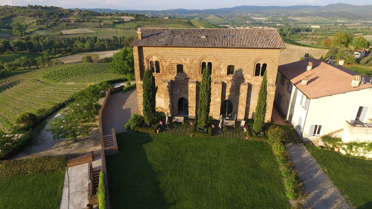 Aerial view of the medieval stone palace at Palazzone, now Locanda Palazzone, with vineyards around it