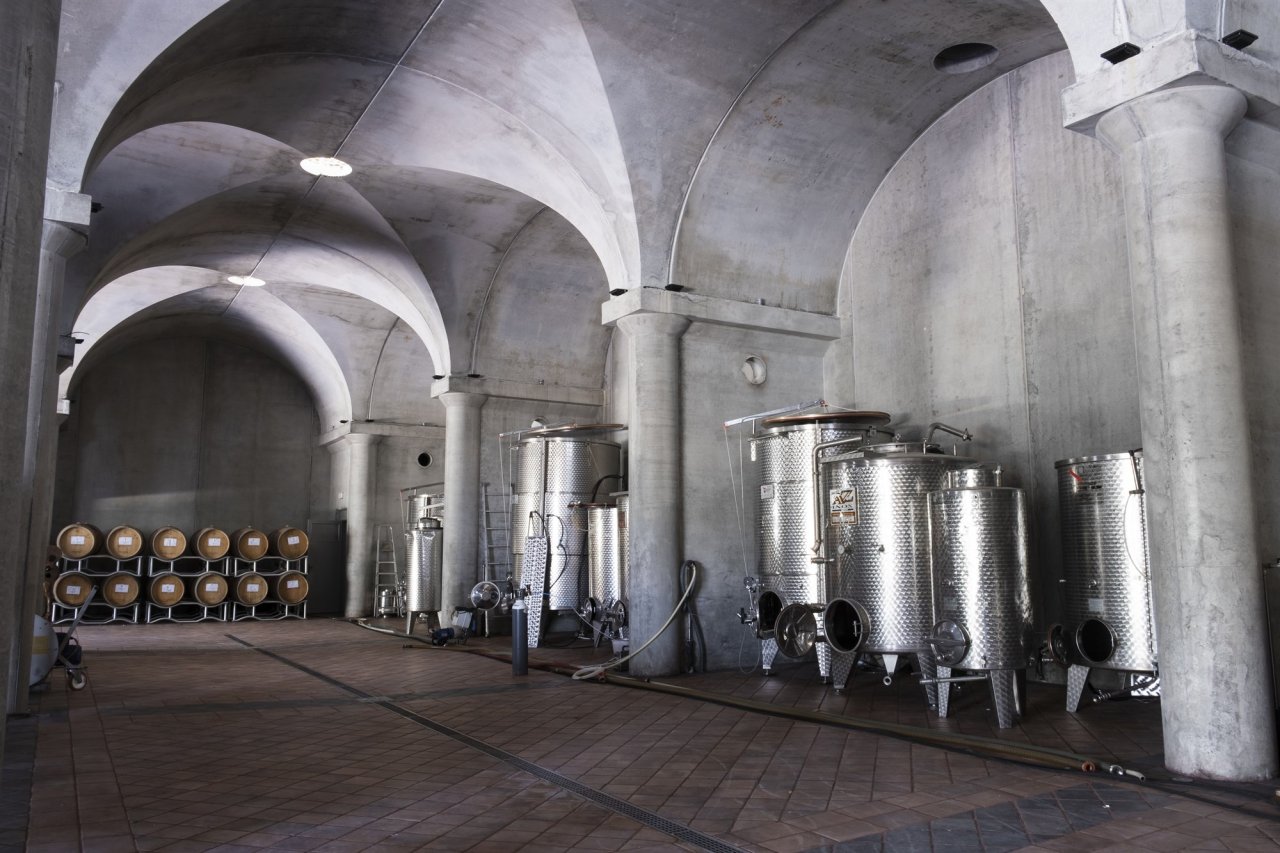 Steel tanks and stacked barrels under the vaulted ceiling of the new cellar at Villa La Ripa