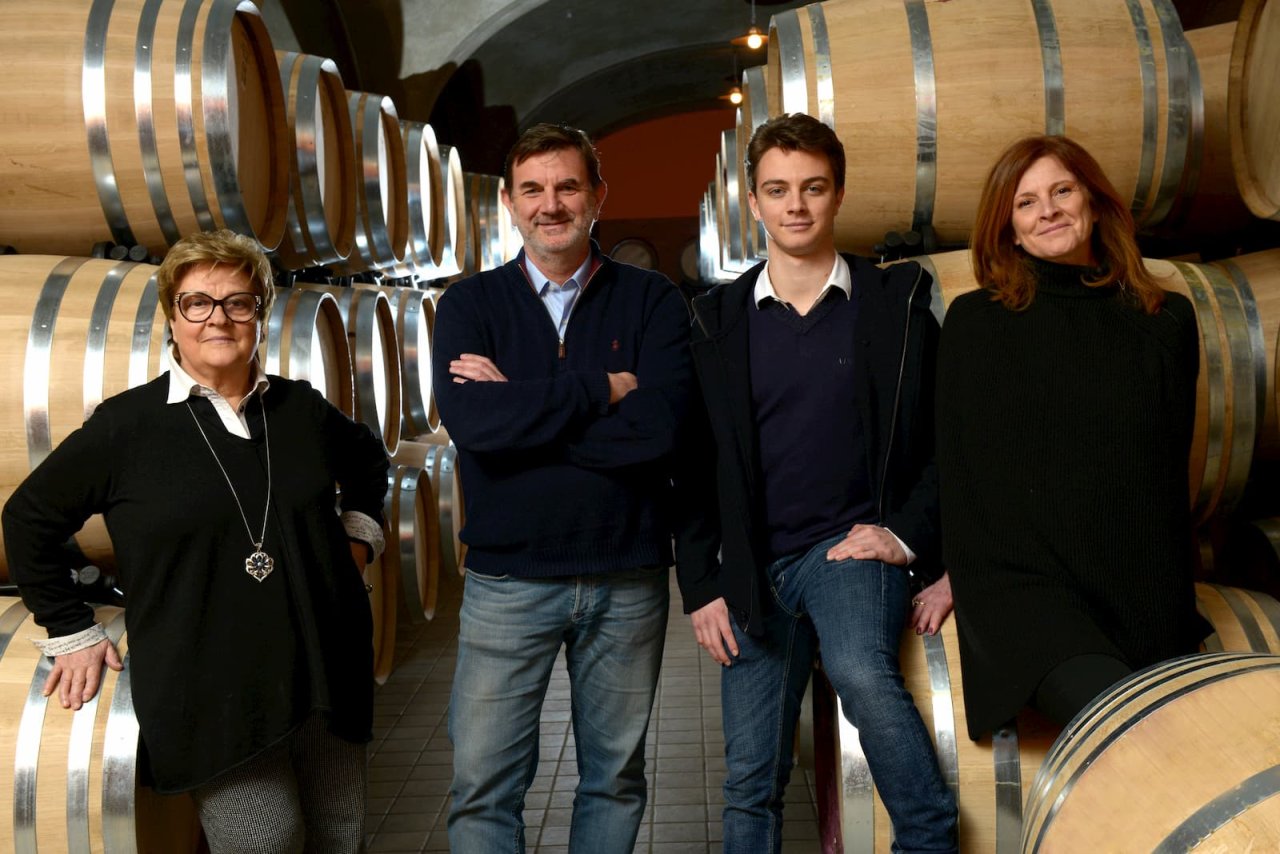 The Tua Rita family, Rita Tua, Stefano Frascolla, Giovanni Frascolla and Simena Bisti, standing among the barrels in the cellar