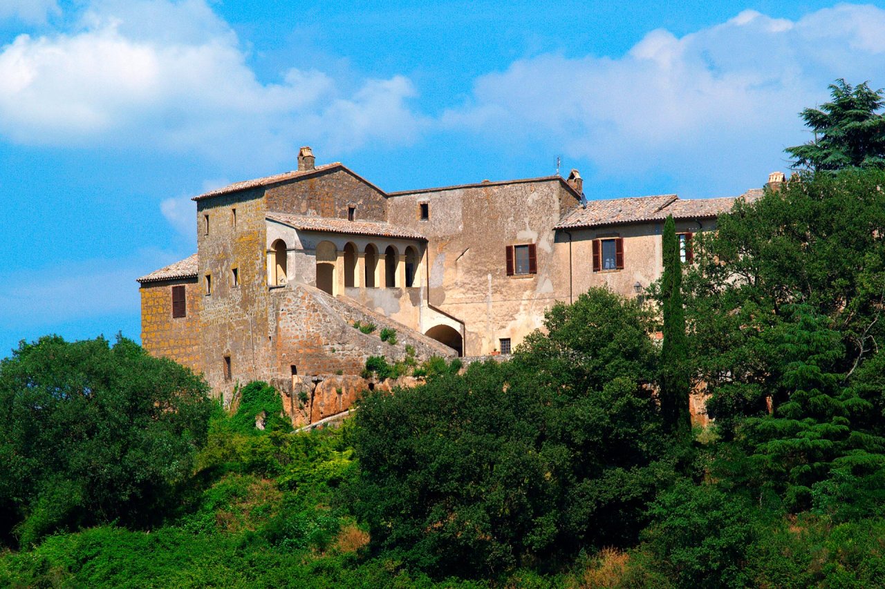 Old stone house with an arched loggia on its upper floor, among trees at Cantine Neri
