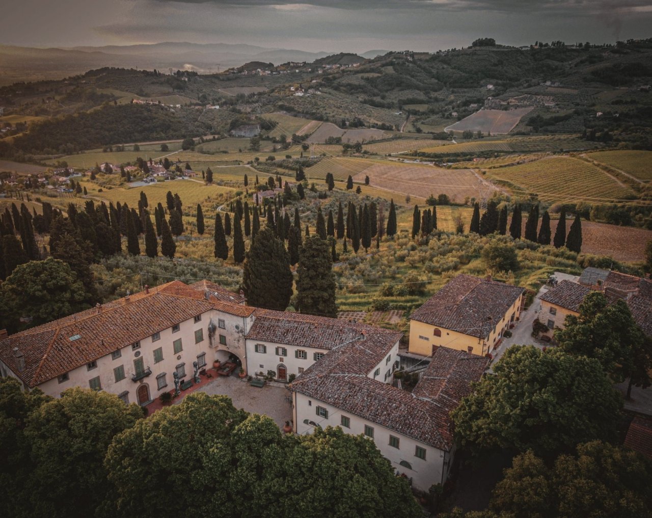 Aerial view of the Tenuta di Capezzana villa and farm buildings with vineyards, olive groves and cypresses behind