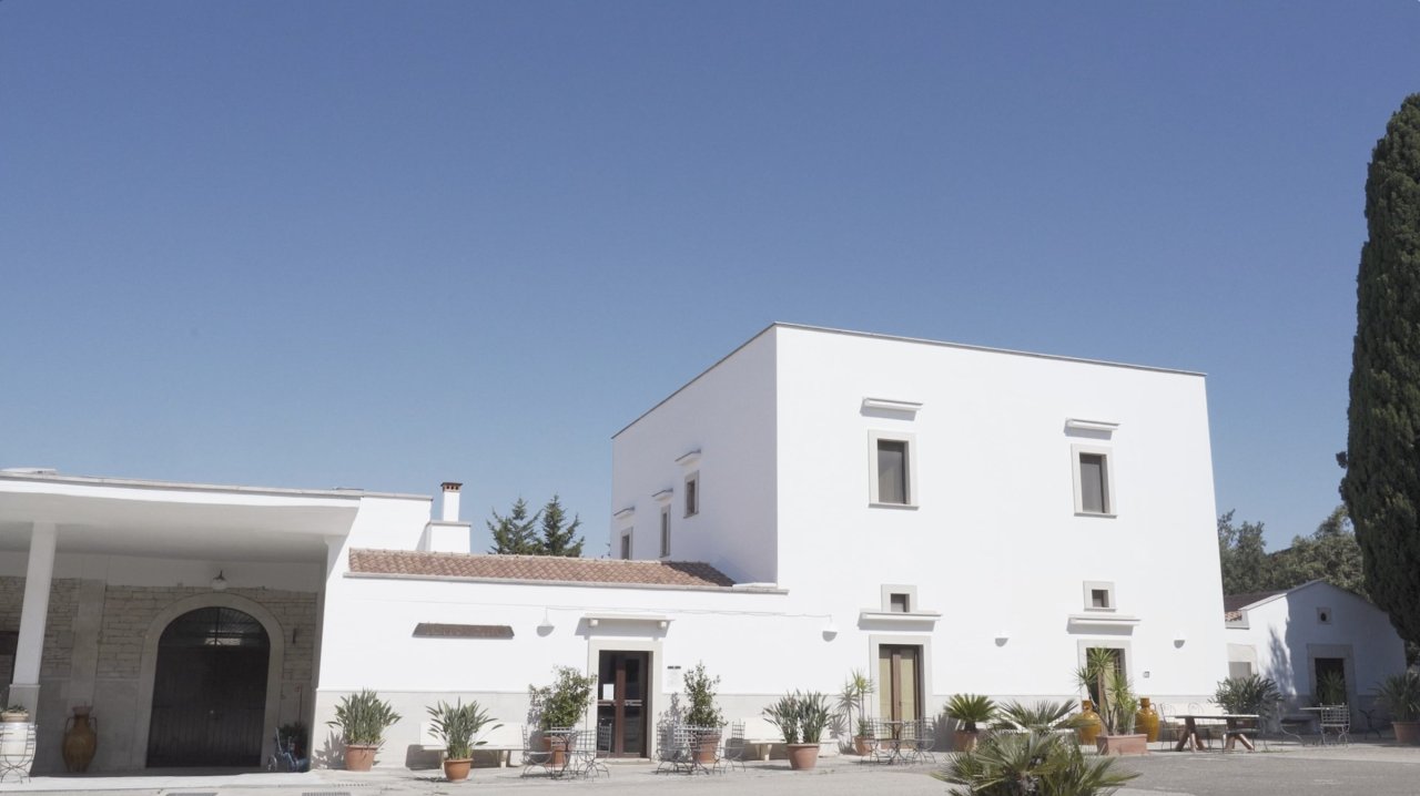 Whitewashed estate buildings with an arched gateway at Torrevento, under a blue sky