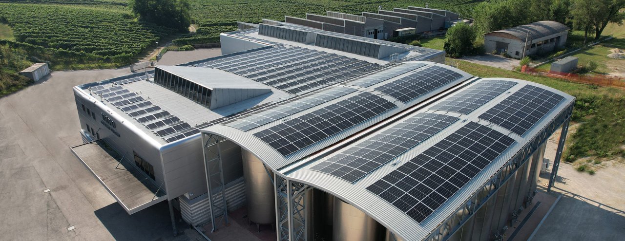 Aerial view of the Valdo Spumanti winery in Valdobbiadene, with solar panels on the roof and vineyards behind